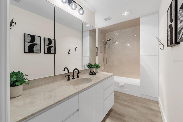 bathroom with hardwood / wood-style floors, vanity, and shower / washtub combination