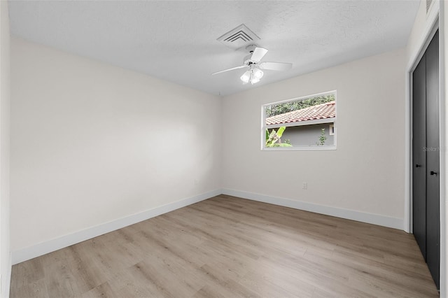 spare room with ceiling fan, light hardwood / wood-style floors, and a textured ceiling