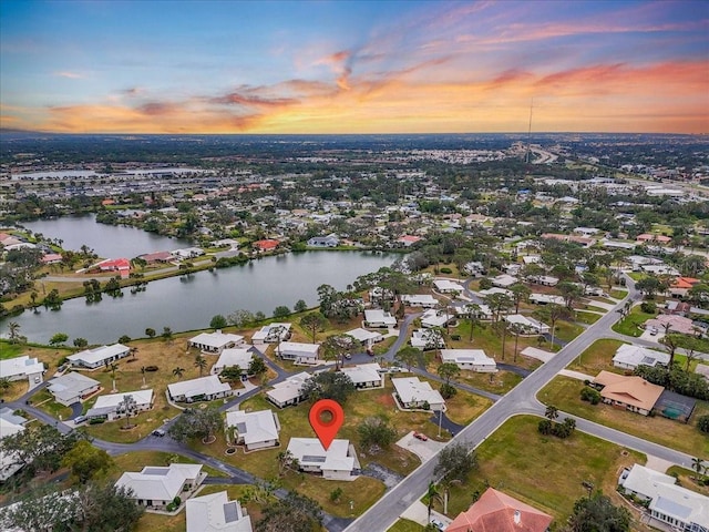 aerial view at dusk featuring a water view