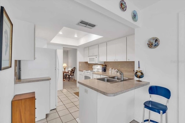 kitchen featuring kitchen peninsula, sink, light tile patterned floors, white appliances, and white cabinets