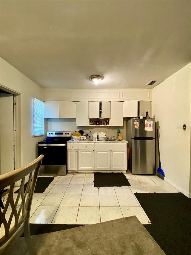 kitchen with white cabinetry, sink, light tile patterned floors, and stainless steel appliances