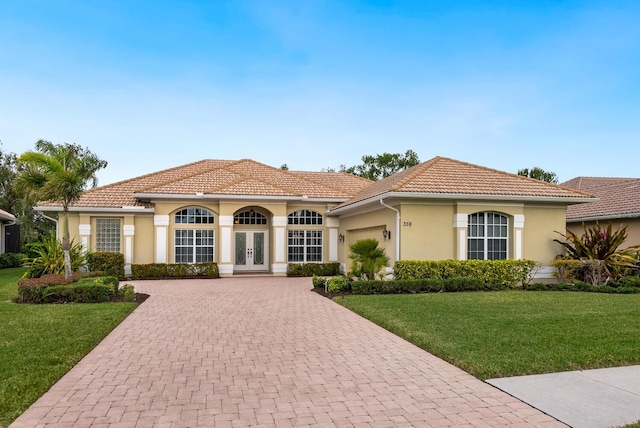 mediterranean / spanish house with a garage, a front lawn, and french doors