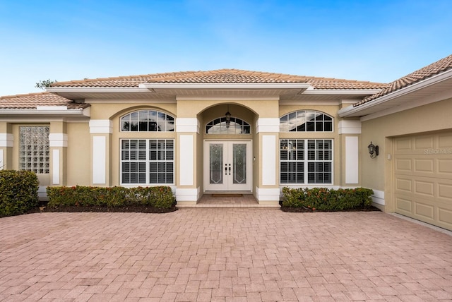 view of exterior entry with a garage and french doors