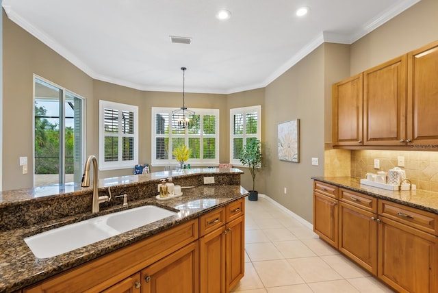 kitchen with sink, pendant lighting, dark stone counters, and a wealth of natural light