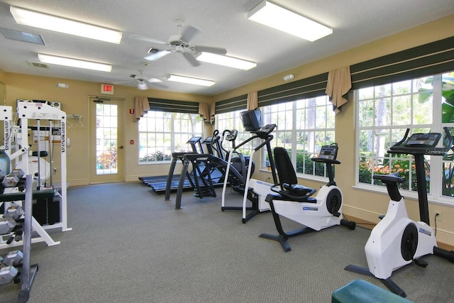 gym with ceiling fan and a textured ceiling