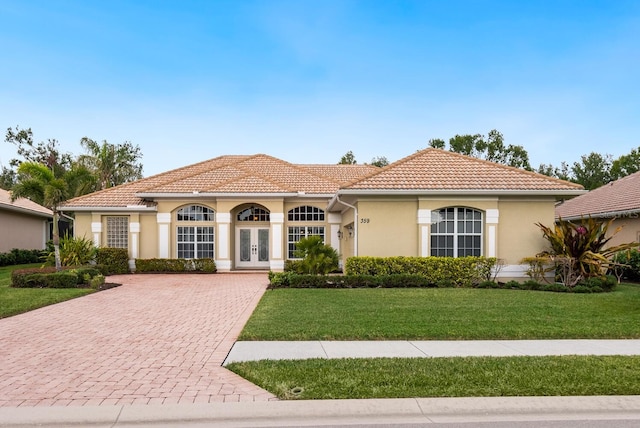 mediterranean / spanish home featuring a front yard and french doors