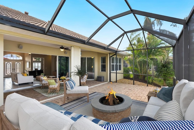 view of patio / terrace with a lanai, ceiling fan, and an outdoor living space with a fire pit