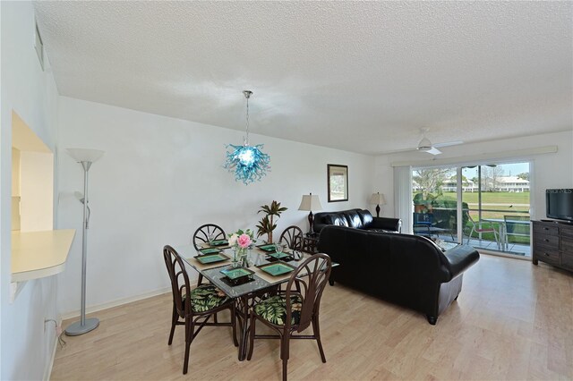 dining area featuring light wood-type flooring, ceiling fan, and a textured ceiling