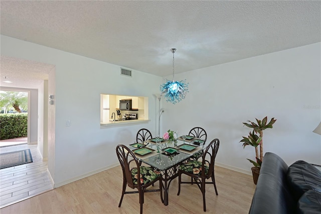 dining room featuring a textured ceiling and light hardwood / wood-style floors