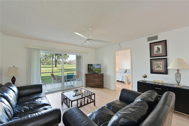 living room featuring a textured ceiling, ceiling fan, and light hardwood / wood-style floors