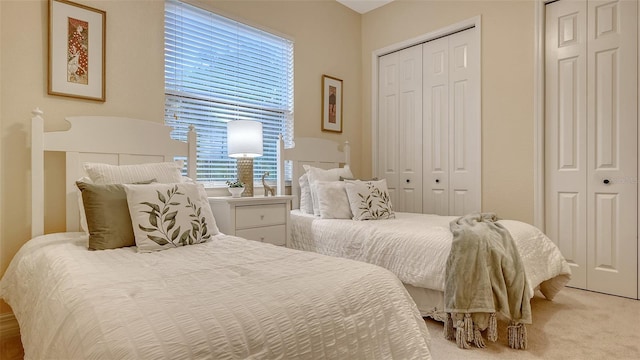 bedroom featuring multiple closets and light carpet