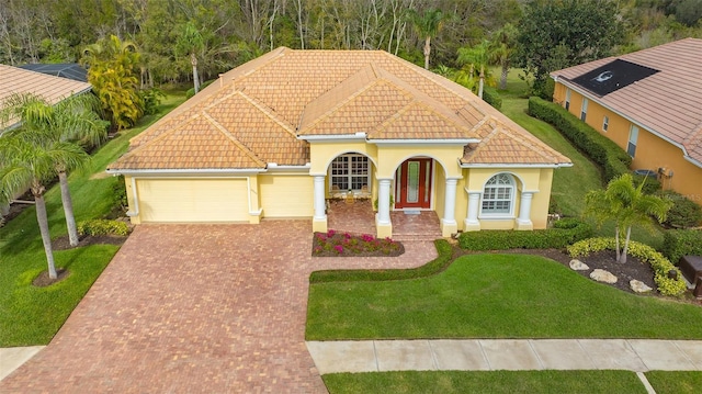 mediterranean / spanish house featuring a garage and a front lawn