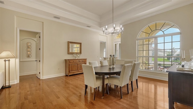 dining space featuring hardwood / wood-style floors, an inviting chandelier, crown molding, and a tray ceiling