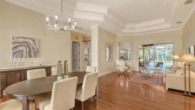 dining area with a tray ceiling, hardwood / wood-style floors, an inviting chandelier, and ornamental molding