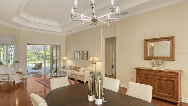 dining room with a chandelier, a raised ceiling, crown molding, and dark wood-type flooring