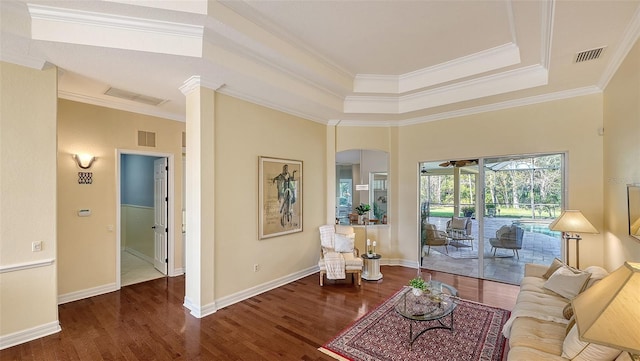 living room with ornamental molding, a raised ceiling, and dark wood-type flooring