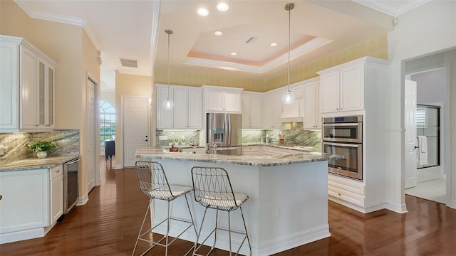 kitchen featuring tasteful backsplash, stainless steel appliances, a raised ceiling, decorative light fixtures, and white cabinets