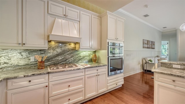 kitchen featuring premium range hood, light stone countertops, stainless steel appliances, and ornamental molding