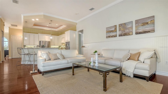 living room featuring hardwood / wood-style floors, a tray ceiling, and ornamental molding