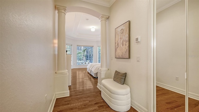 hall with dark hardwood / wood-style flooring, ornate columns, and crown molding