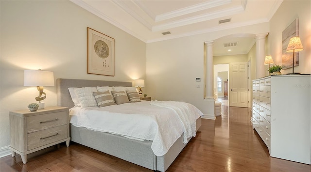 bedroom featuring a tray ceiling, ornate columns, dark hardwood / wood-style floors, and ornamental molding