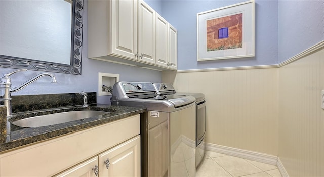 washroom with cabinets, washing machine and dryer, light tile patterned floors, and sink