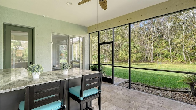 sunroom / solarium featuring a wealth of natural light and ceiling fan