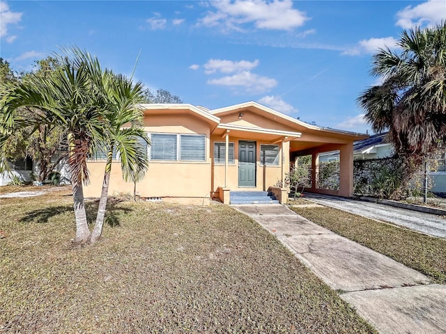 view of front of house featuring driveway, an attached carport, a front lawn, and stucco siding