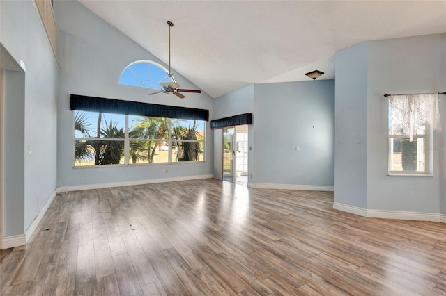 unfurnished living room featuring ceiling fan, light wood-type flooring, and high vaulted ceiling