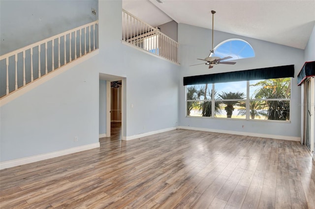 unfurnished living room with ceiling fan, hardwood / wood-style floors, and a high ceiling