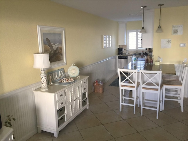 dining space with a wainscoted wall and tile patterned floors