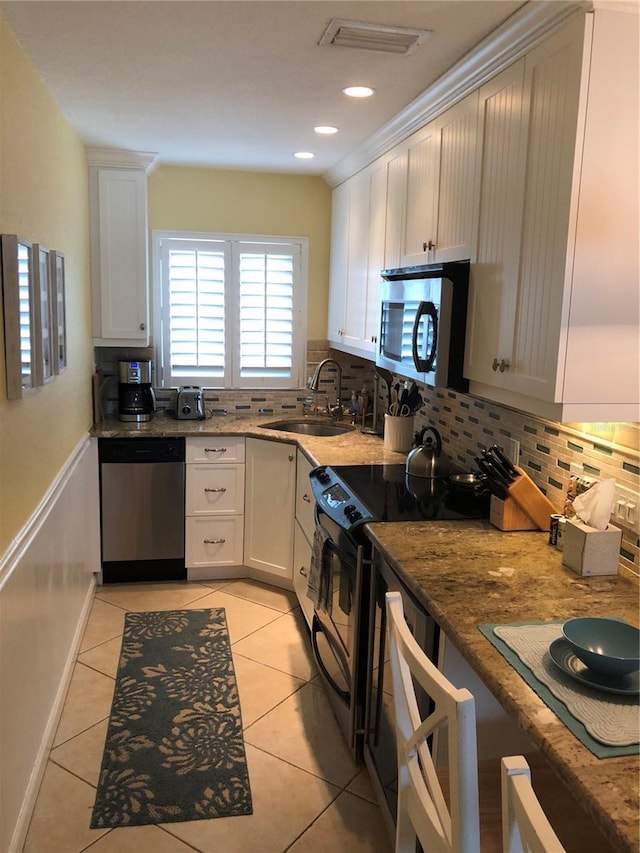 kitchen featuring light tile patterned floors, stainless steel appliances, a sink, and decorative backsplash