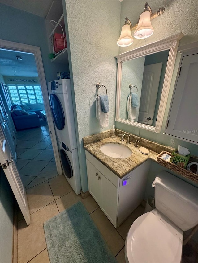 bathroom featuring toilet, tile patterned floors, a textured wall, and vanity