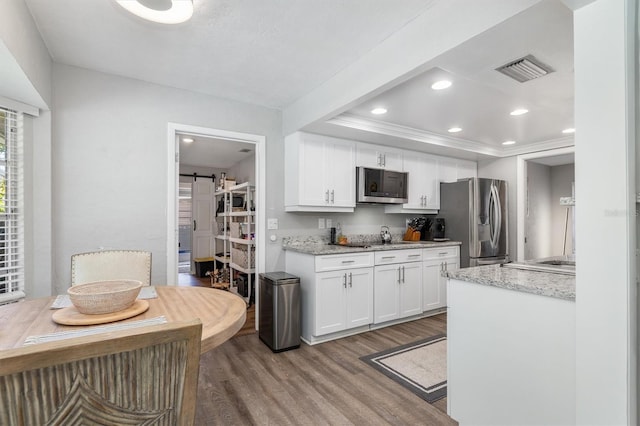 kitchen featuring white cabinets, a barn door, light stone countertops, and stainless steel appliances