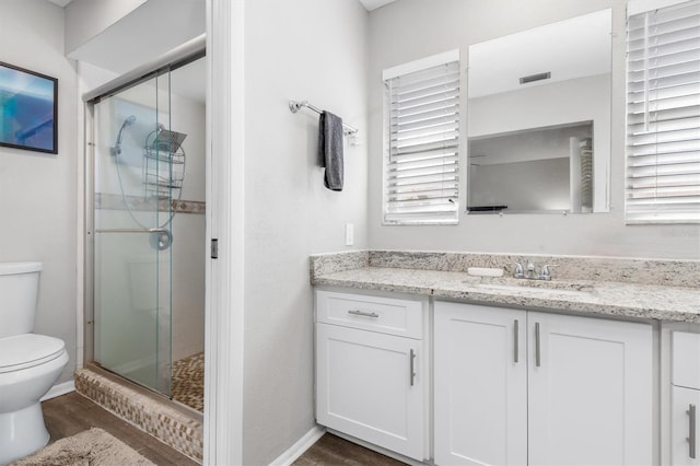 bathroom featuring hardwood / wood-style flooring, vanity, an enclosed shower, and toilet