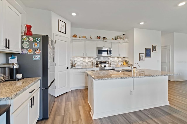 kitchen with sink, white cabinetry, stainless steel appliances, and an island with sink