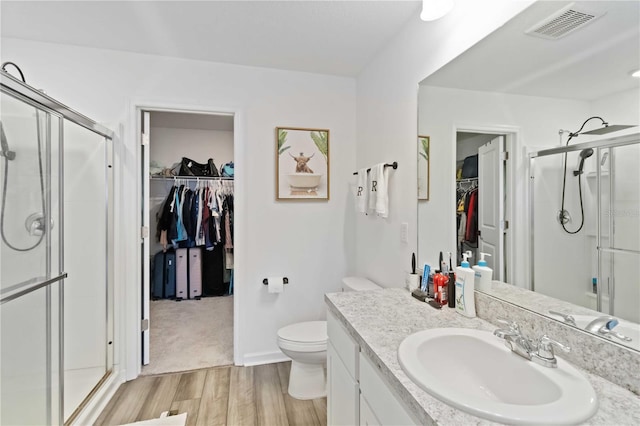 bathroom featuring hardwood / wood-style flooring, vanity, toilet, and a shower with door