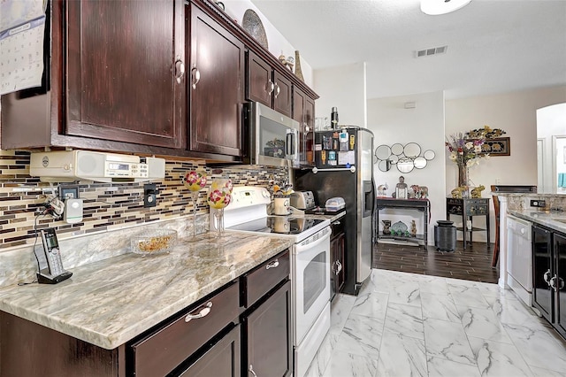 kitchen featuring tasteful backsplash, dark brown cabinetry, light stone counters, and stainless steel appliances