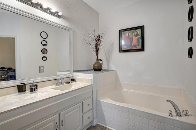 bathroom with vanity and tiled tub