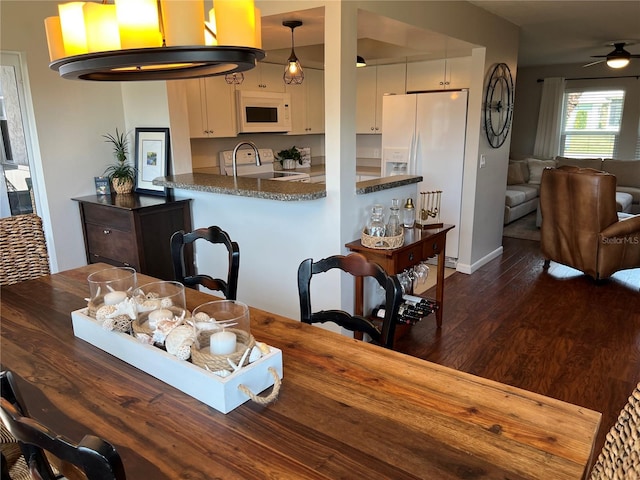 kitchen with pendant lighting, white appliances, dark stone counters, and white cabinets