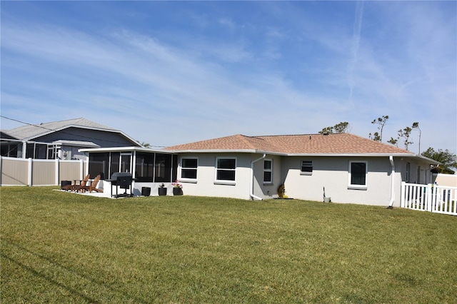 rear view of property featuring a patio area, a sunroom, and a lawn