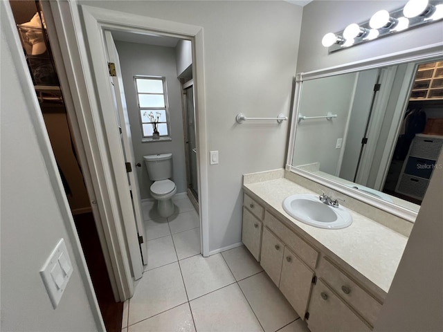 bathroom featuring toilet, vanity, tile patterned floors, and a shower with shower door