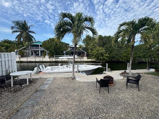 view of yard with a dock, a water view, and a fire pit