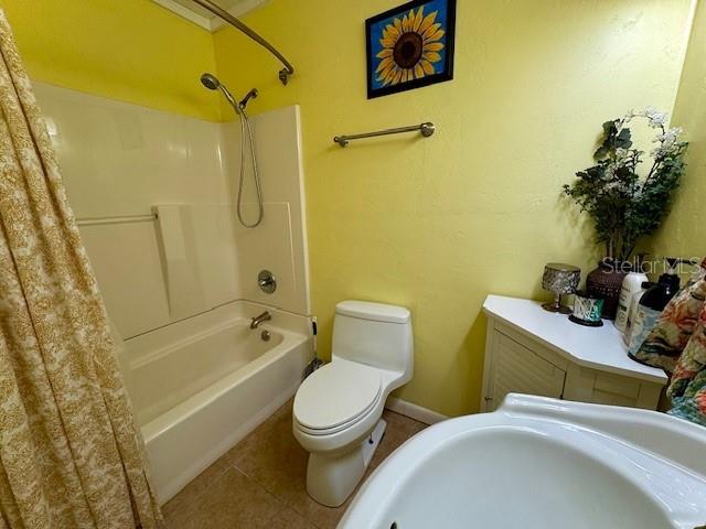 full bathroom with toilet, shower / bath combo, tile patterned floors, and sink