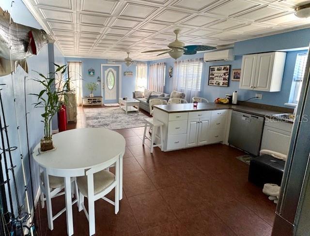 kitchen with kitchen peninsula, white cabinets, a wall mounted AC, ceiling fan, and dishwasher