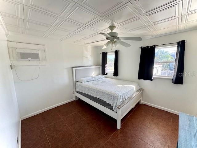 unfurnished bedroom featuring dark tile patterned flooring, ceiling fan, and a wall mounted AC