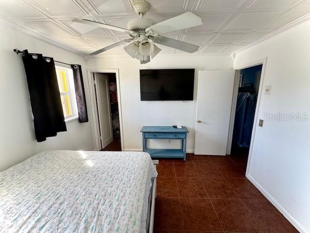 tiled bedroom with ceiling fan, a spacious closet, and a closet