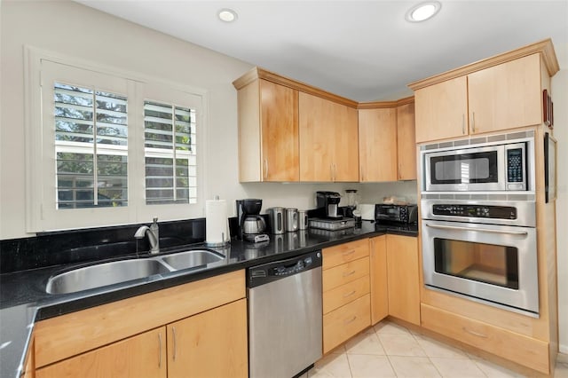 kitchen featuring light tile patterned flooring, appliances with stainless steel finishes, light brown cabinetry, and sink