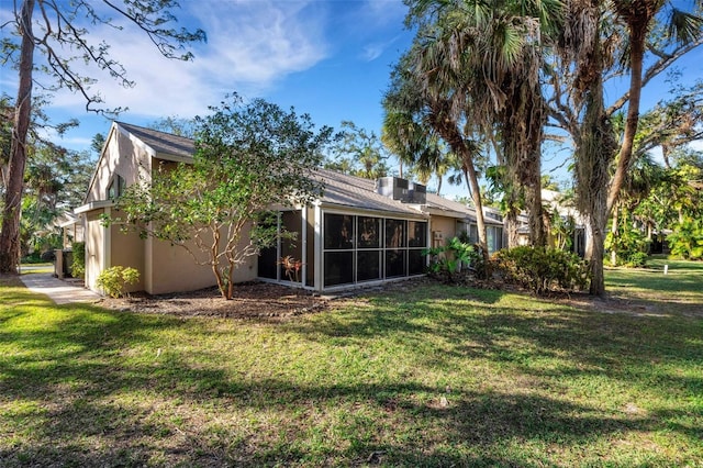 rear view of property with a sunroom and a lawn