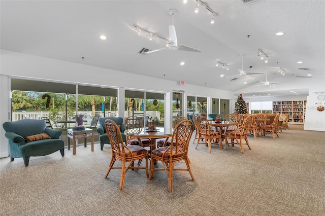 dining space with a wealth of natural light, ceiling fan, light colored carpet, and vaulted ceiling